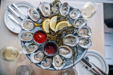 Fresh oysters with various sauces and lemon on ice tray served in a luxury restaurant