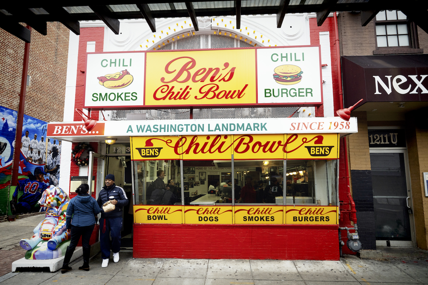 the outside of ben's chili bowl in washington dc with a couple people standing in front