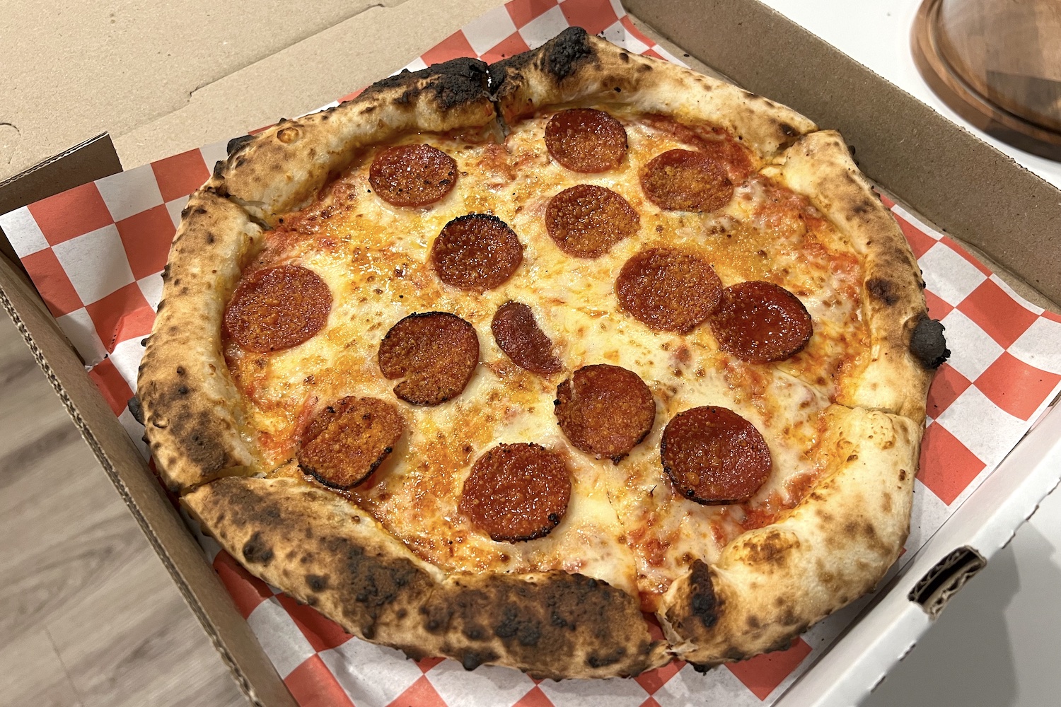 Grata's pepperoni pie in a pizza box on top of white and red checked paper