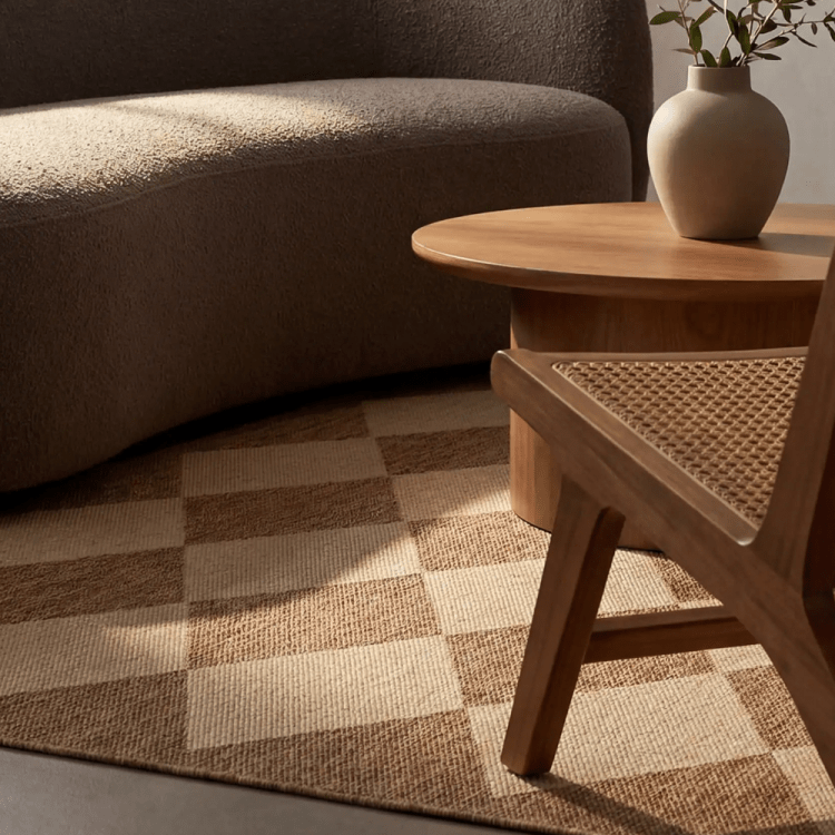lifestyle image focused on harlequin patterned rug with a couch, chair and coffee table sitting on top