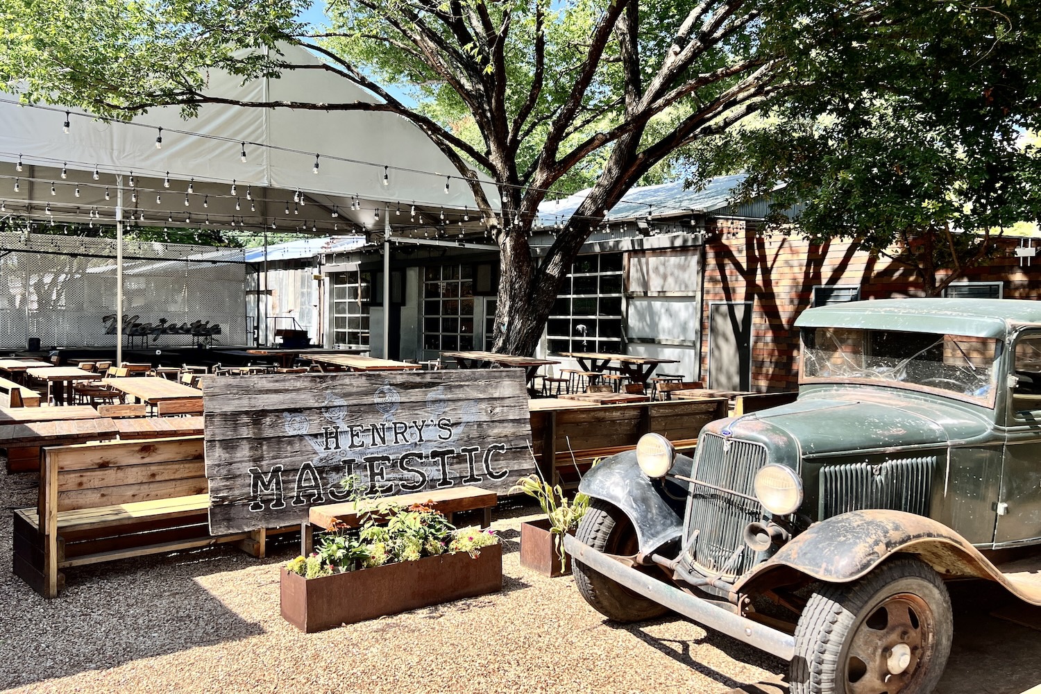 old vintage care parked outside a wooden sign, trees, benches