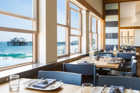 blue chairs, tables, utensils, napkins, plates, glasses, windows open, ocean view