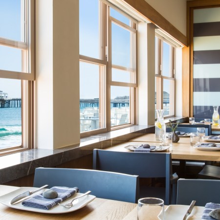 blue chairs, tables, utensils, napkins, plates, glasses, windows open, ocean view