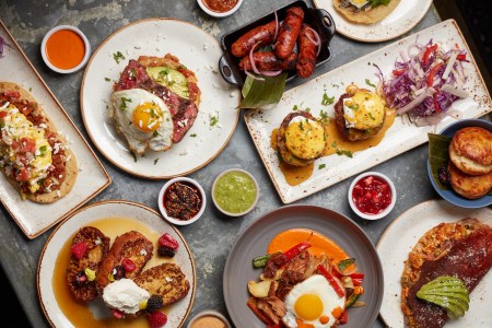 different plates of brunch food, sausages, eggs, meat, french toast with berries