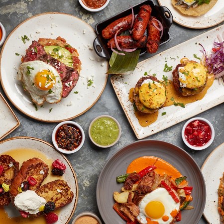 different plates of brunch food, sausages, eggs, meat, french toast with berries