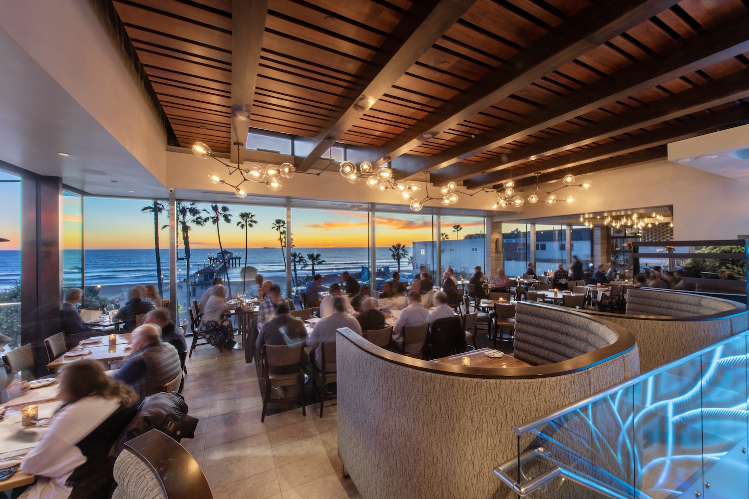 people sitting, eating, lights, glass windows, ocean and palm tree views