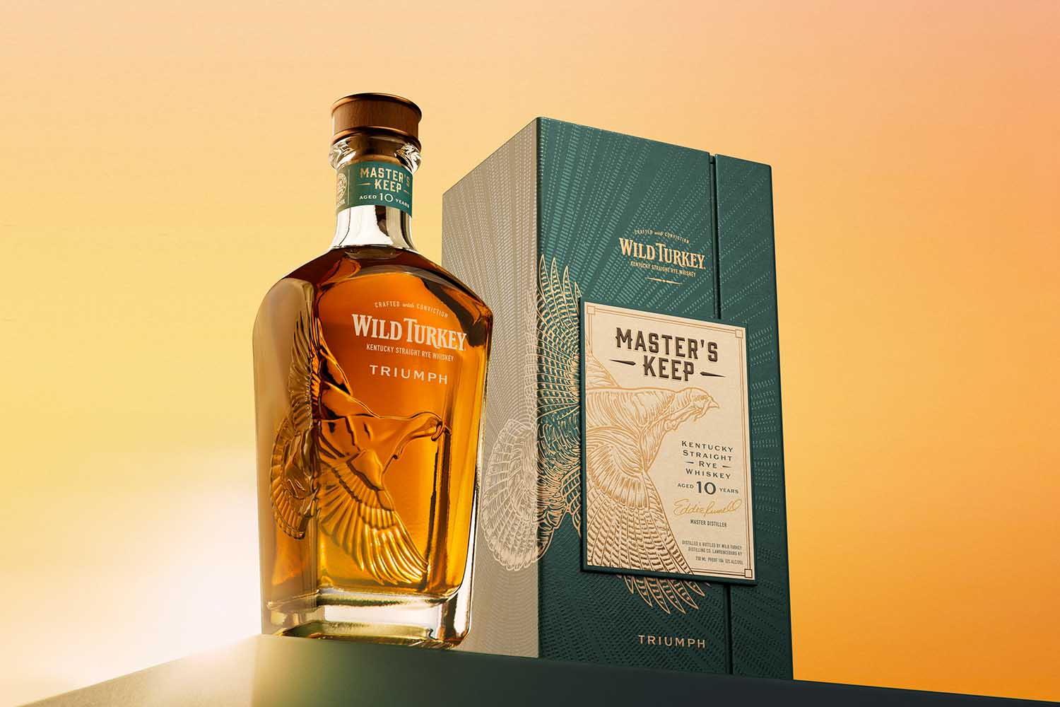 Wild Turkey Masters Keep Triumph, both the bottle and the packaging, on a table.