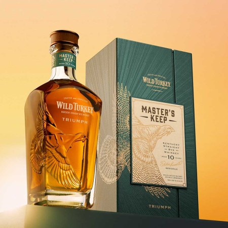 Wild Turkey Masters Keep Triumph, both the bottle and the packaging, on a table.