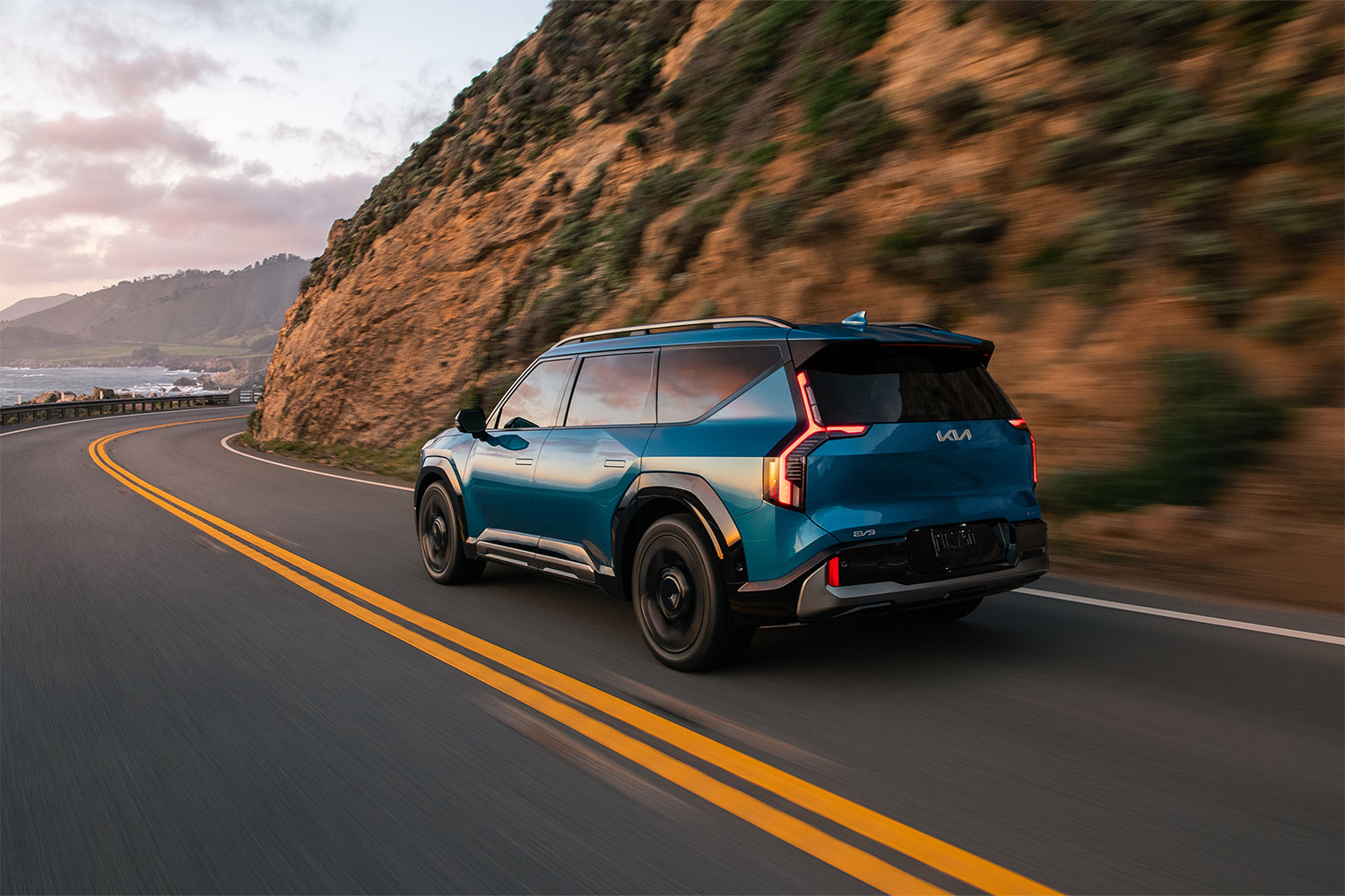 2024 Kia EV9 GT-Line driving around a turn next to a cliff