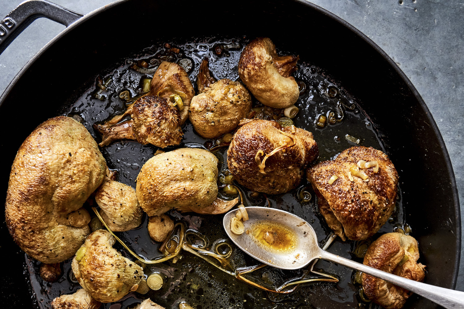 a cast iron pan with lions mane mushrooms, sauteed green garlic and a metal spoon