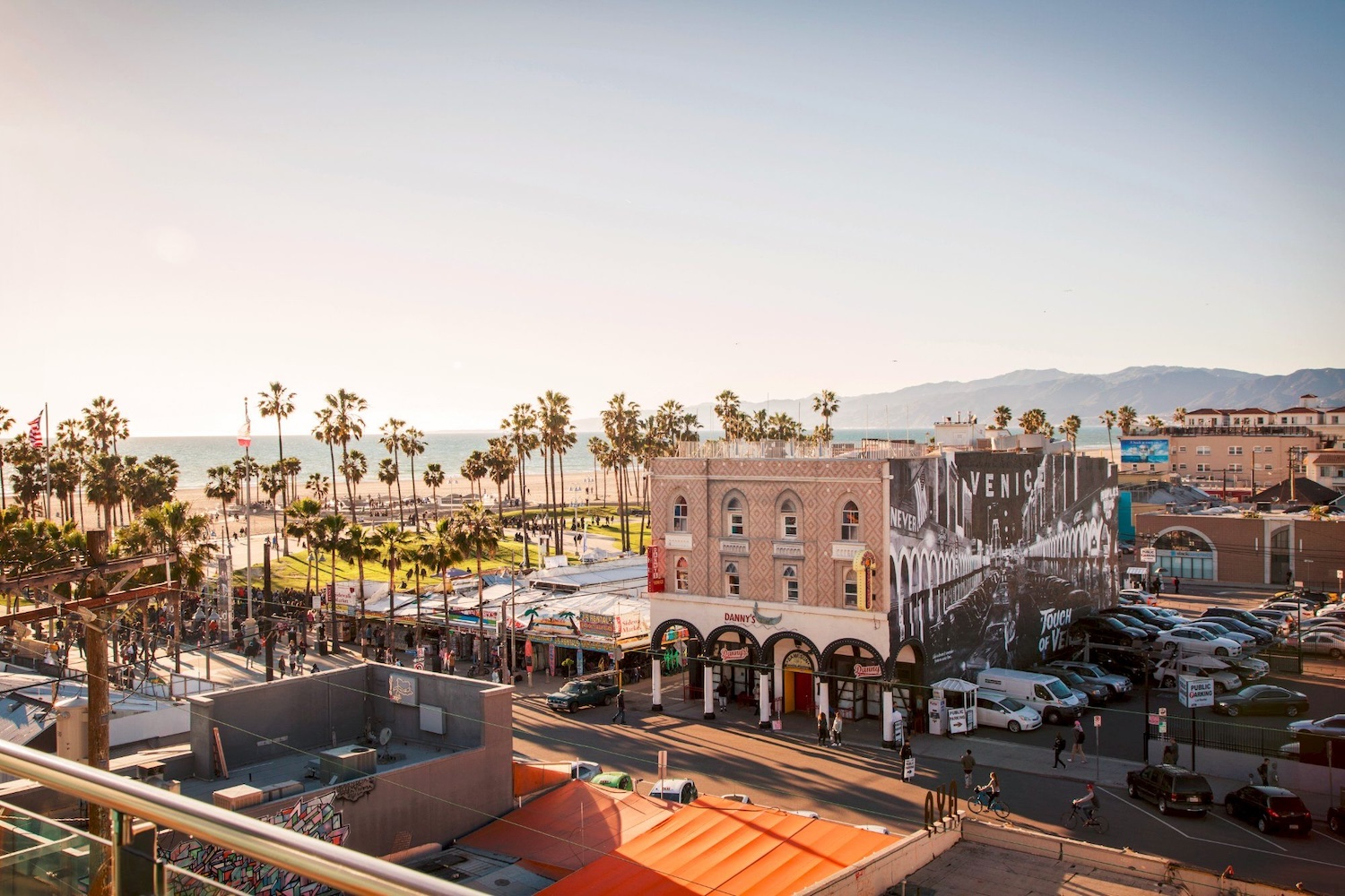 buildings, cars, people palm trees, mountains, beach, ocean,