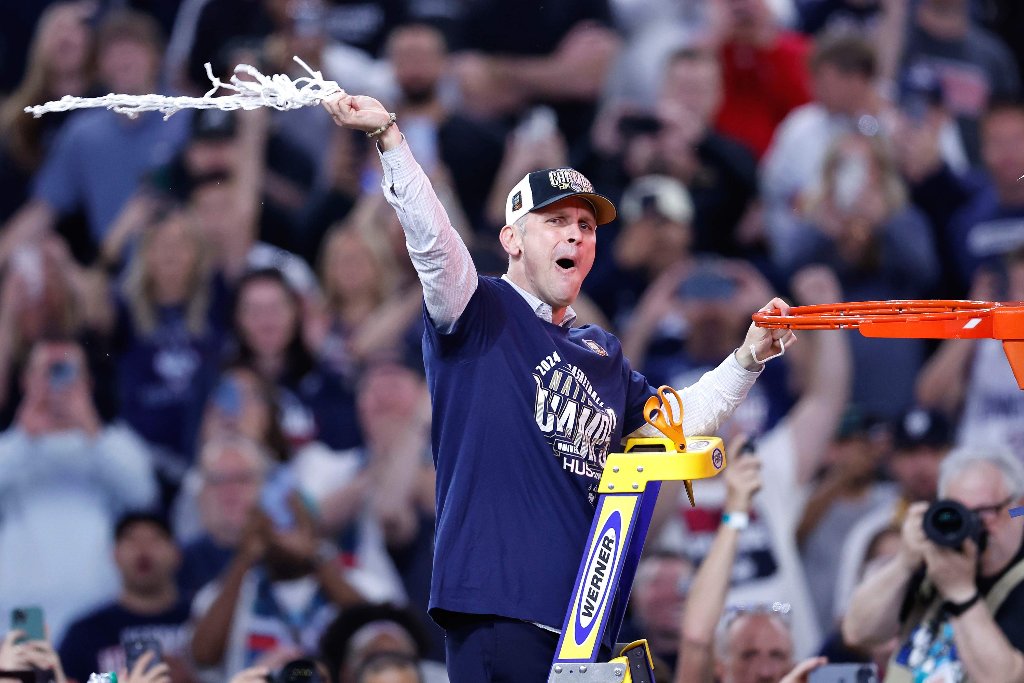 Coach Dan Hurley of the Huskies cuts down the net.