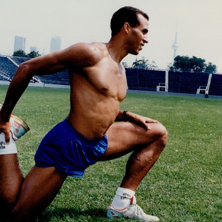 A fit man stretching on a turf field without a shirt