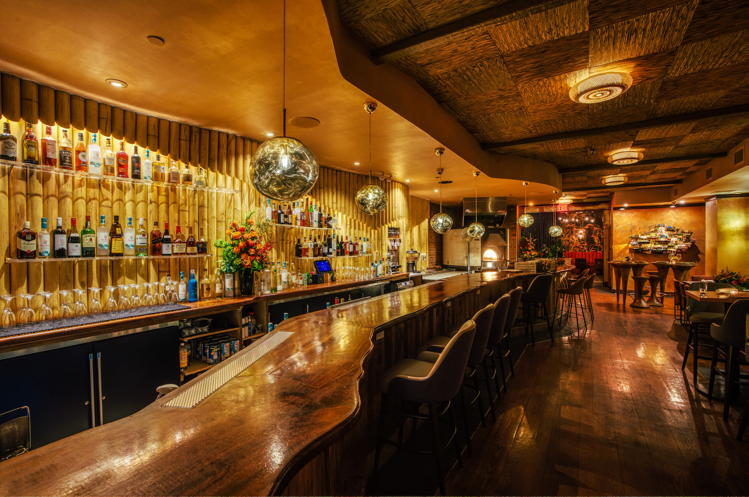 Bar area at Kokomo, with dim lighting and a wall lined in bamboo and disco bal light fixtures