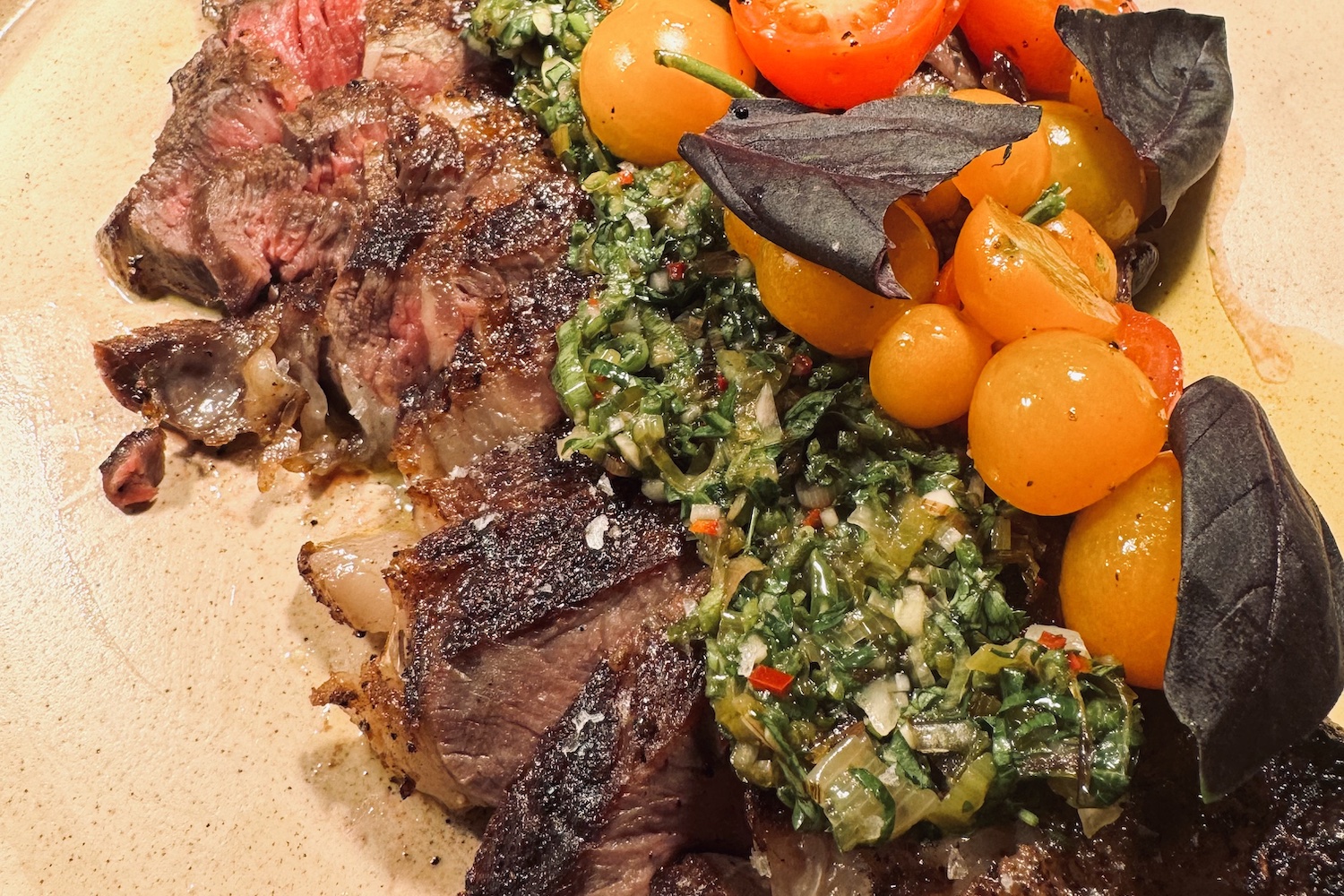 a steak topped with salsa verde and fresh cherry tomatoes