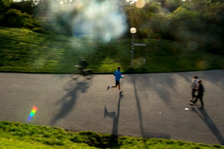 A man running through a park as the sun sets.