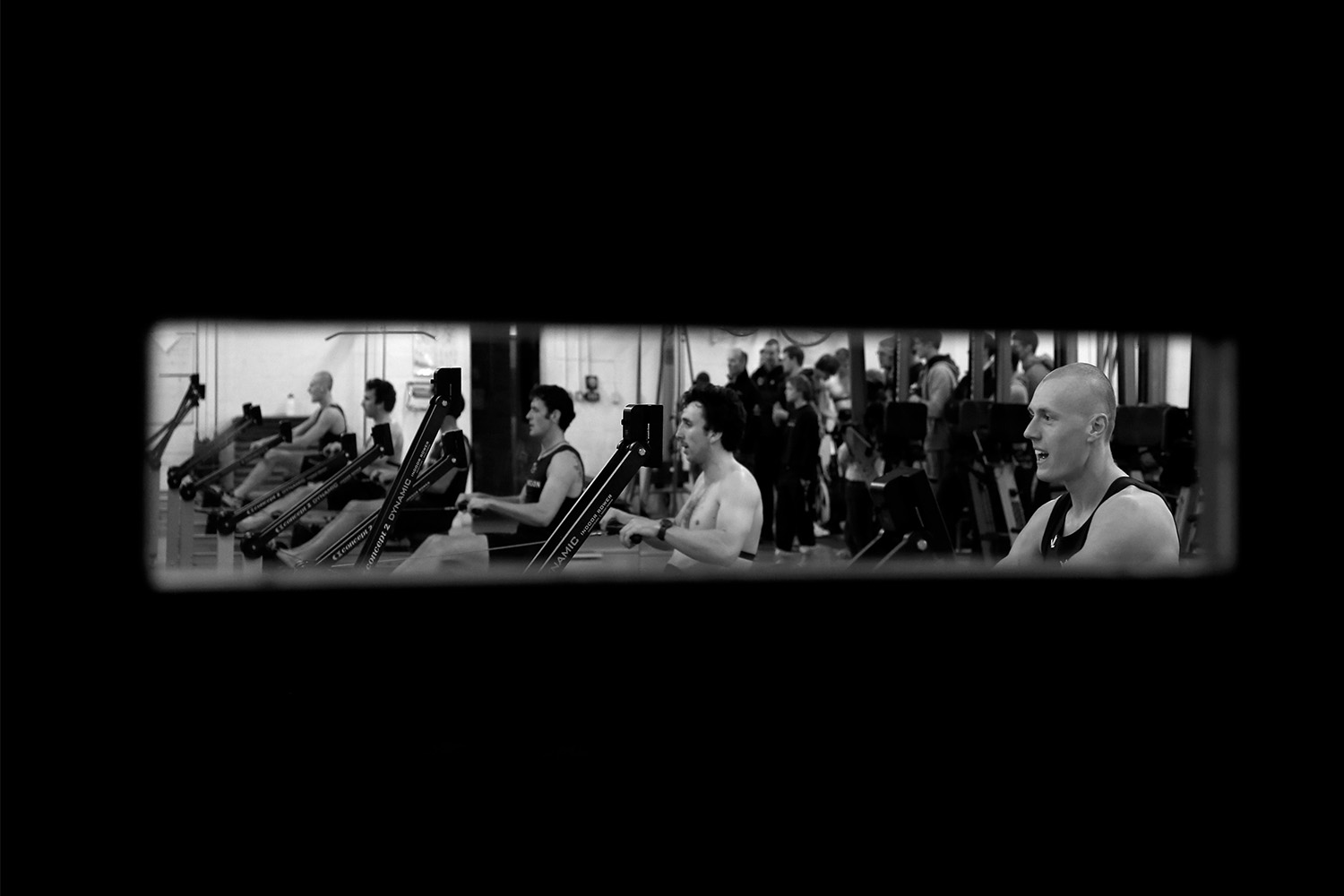 A group of men rowing indoors, black and white photo.