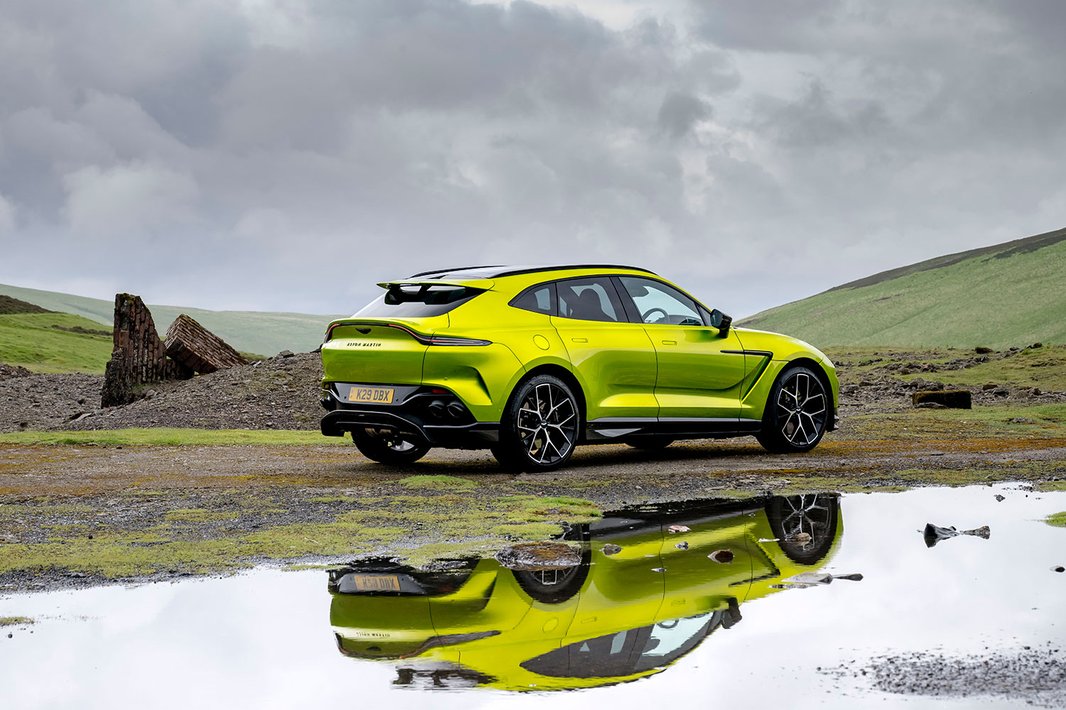 A Photon Lime Aston Martin DBX707 in rural Scotland, with its reflection seen in a pool of water