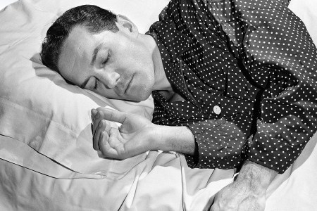 a black and white photo of a man sleeping in polka dot pajamas