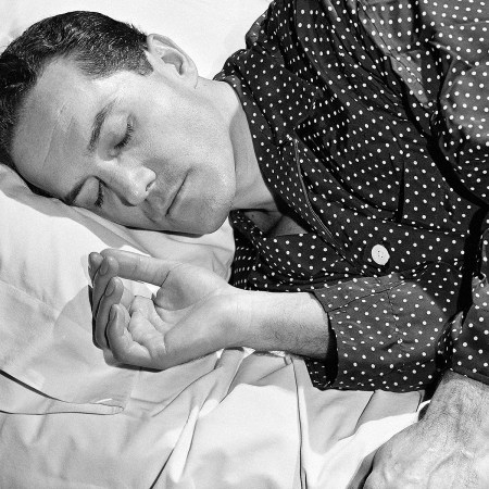 a black and white photo of a man sleeping in polka dot pajamas