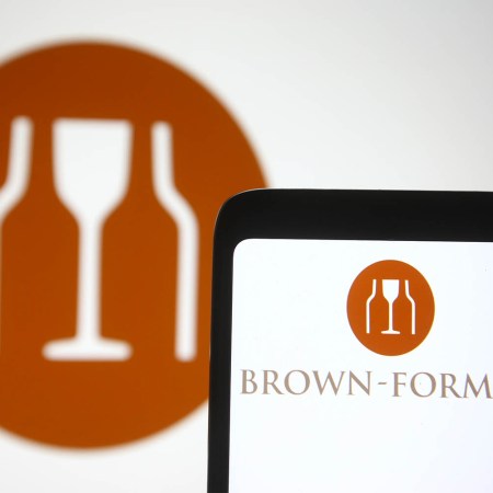 In this photo illustration a BrownForman logo is seen on a smartphone and a pc screen