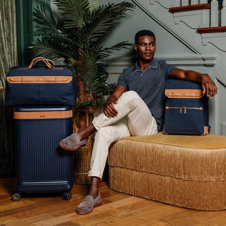 A man sitting with luggage from the new Hartmann Reserve Collection
