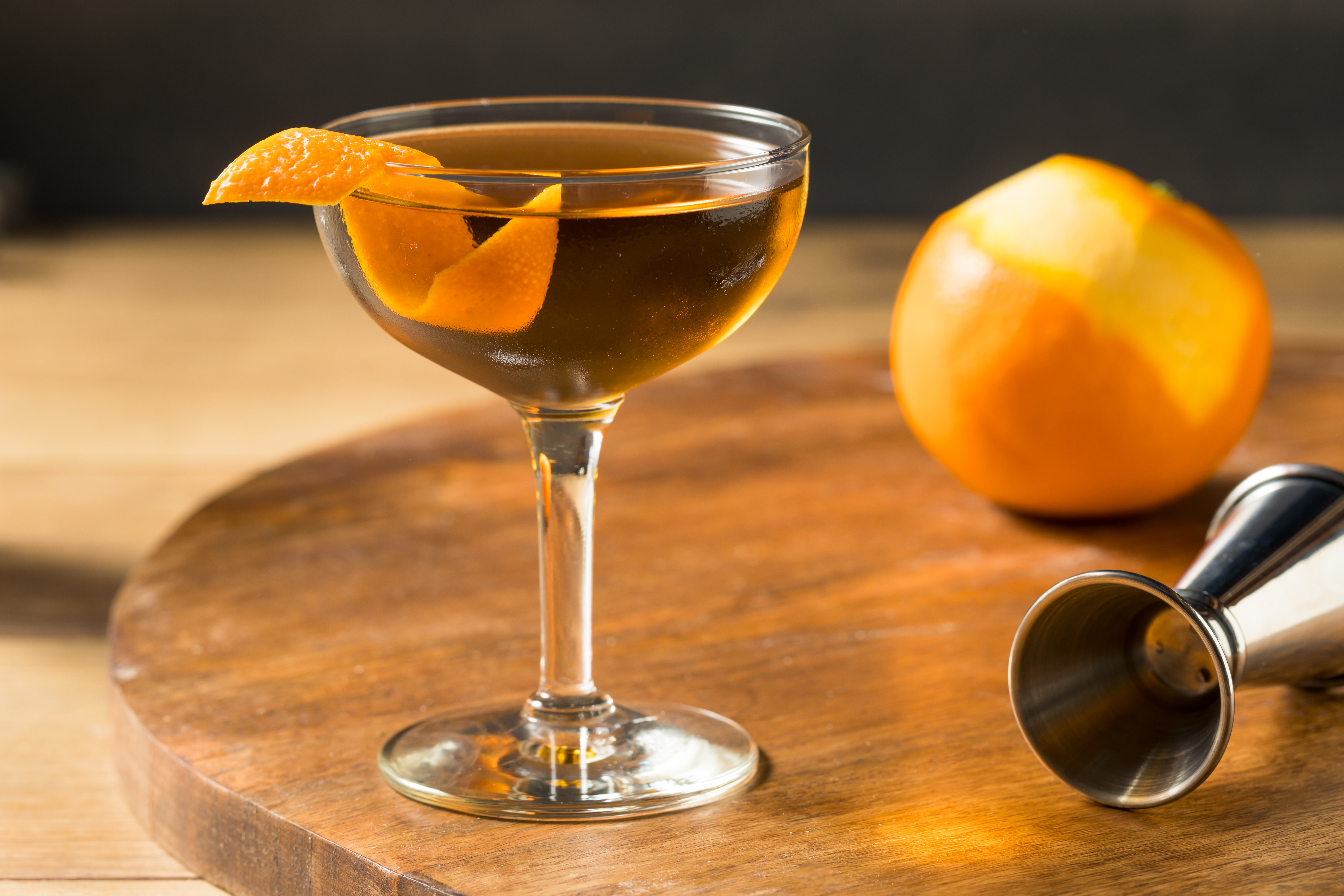 a hanky panky cocktail on a wooden table with a jigger and orange
