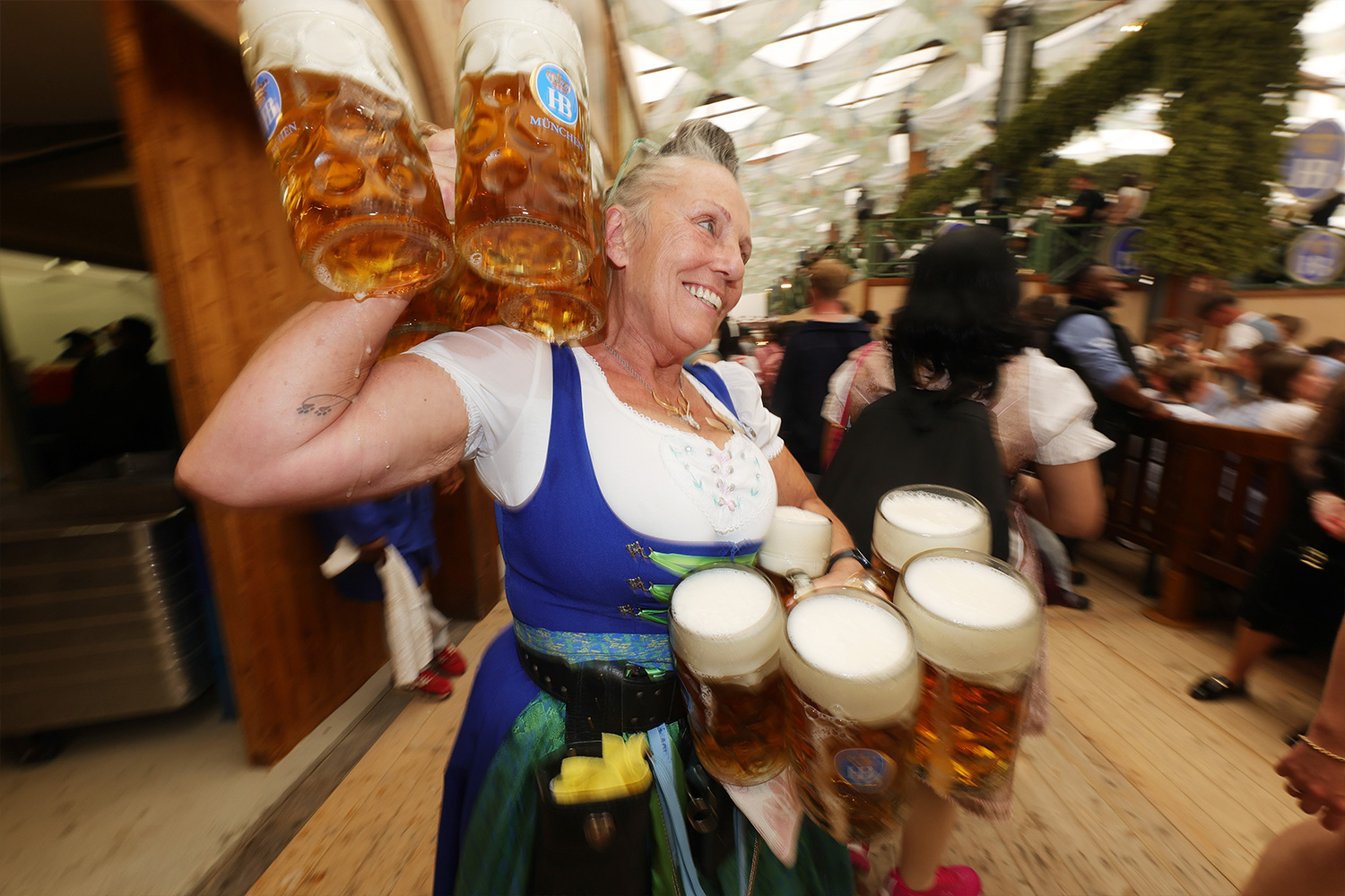 A server carries beer mugs inside the Hofbraeuhaus beer tent on the opening day of the 2024 Munich Oktoberfest