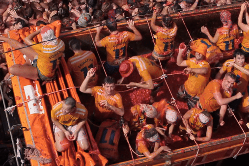 Tomatina volunteers throw tomatoes from a truck on the street of Bu̱ol, Valencia, Spain.