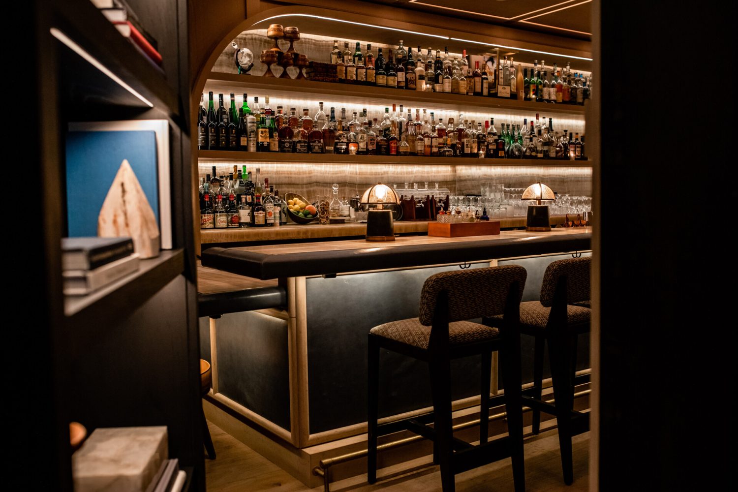 Bookcase doorway that opens up to a bar