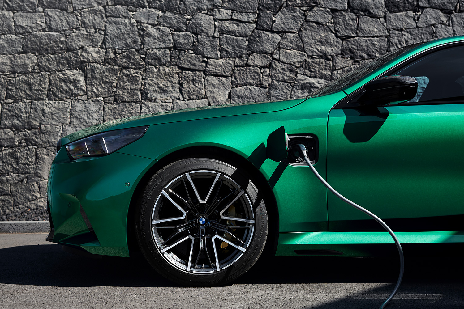 2025 BMW M5 in green with a charger plugged in