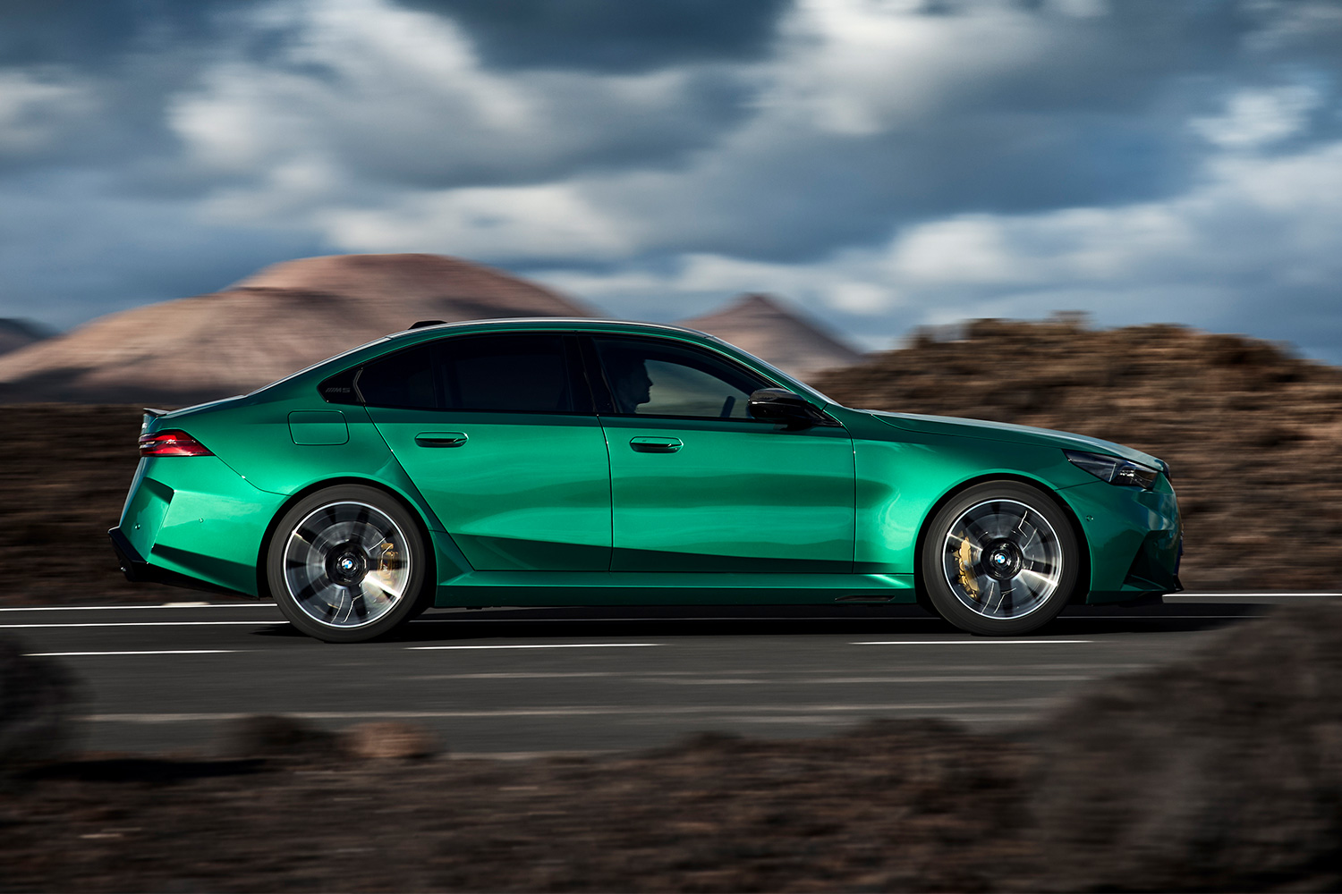 The all-new BMW M5 plug-in hybrid sports sedan driving down the road