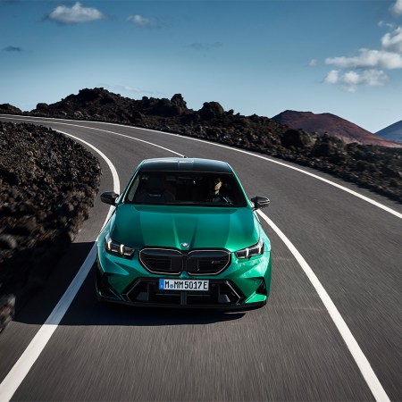 A 2025 BMW M5 in green driving down the road