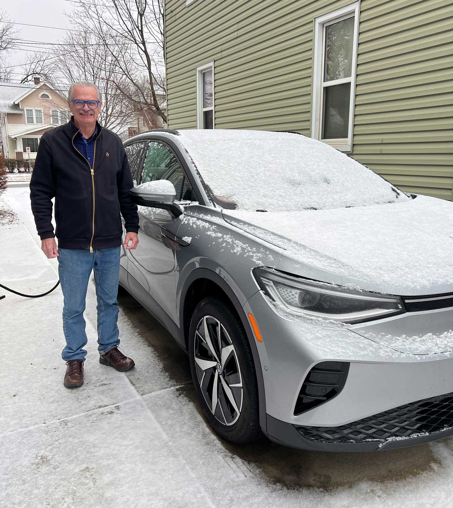 A Minnesota man standing next to his Volkswagen ID.4 EV in the snow