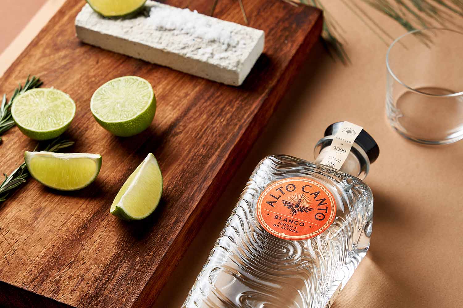 Alto Canto blanco tequila near salt and limes on a table