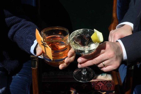 Two people cheers-ing and clinking glasses filled with booze