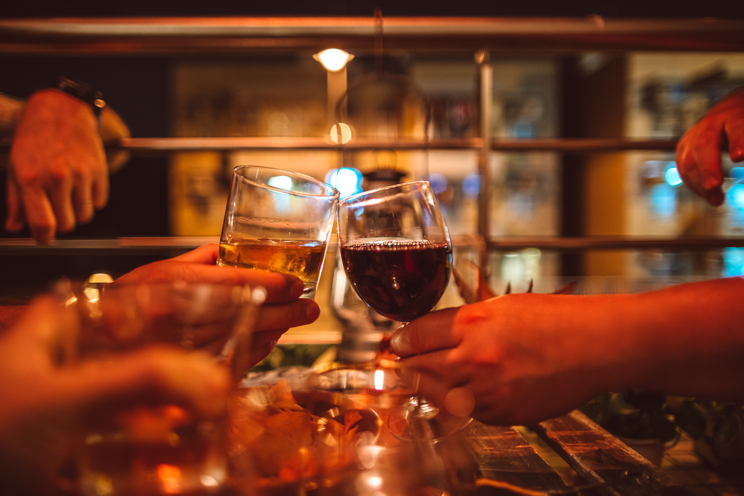 Friends toasting wine and whiskey in celebratory party on balcony at home