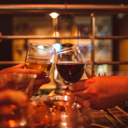 Friends toasting wine and whiskey in celebratory party on balcony at home