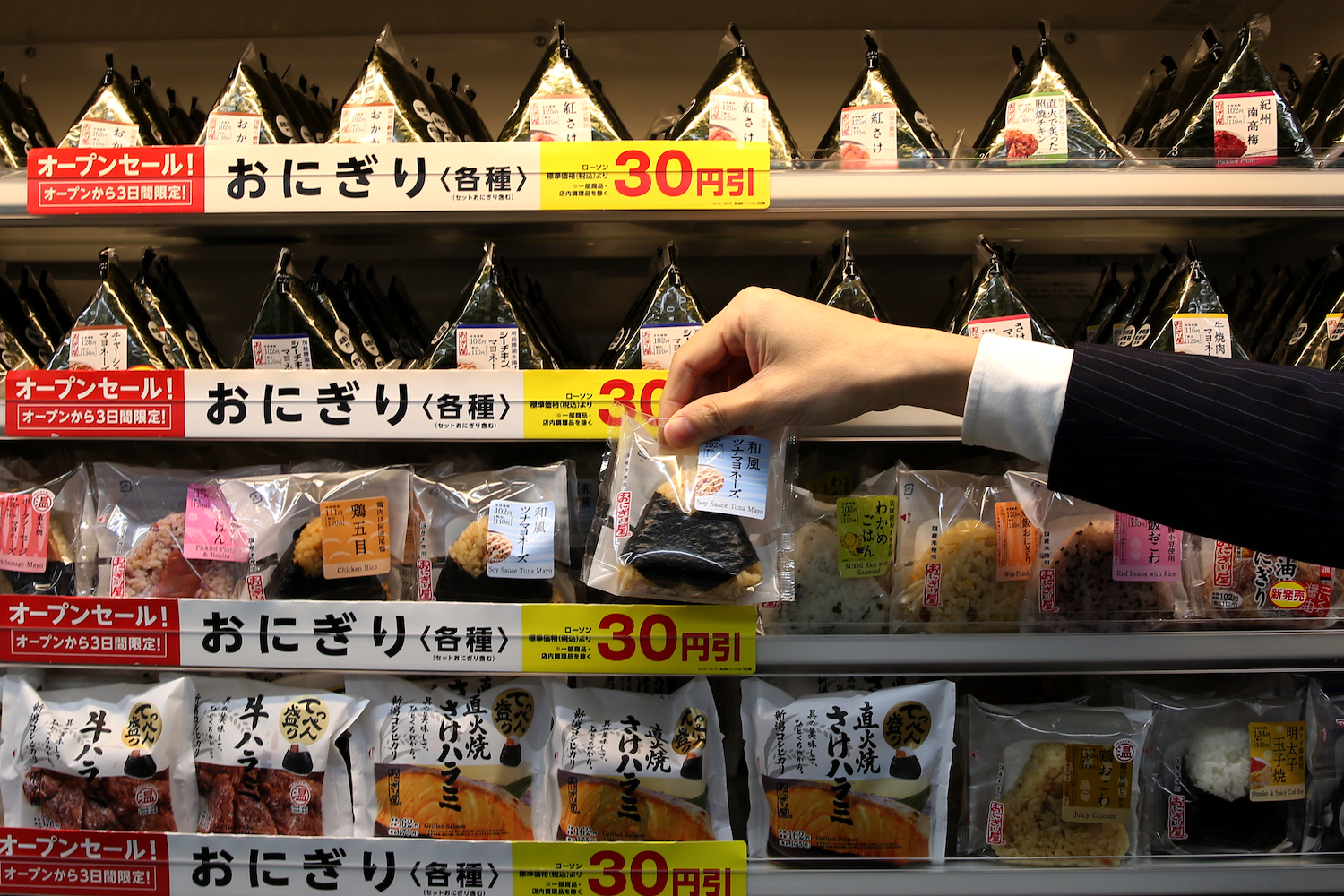 An employee arranges Onigiri, rice balls at a newly designed train-shaped convenience store named Lawson + Friends