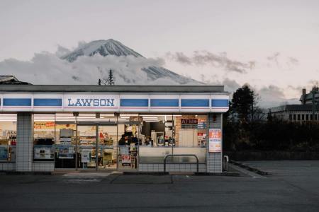 a japanese lawson konbini at dusk in front of a snow-covered mountain