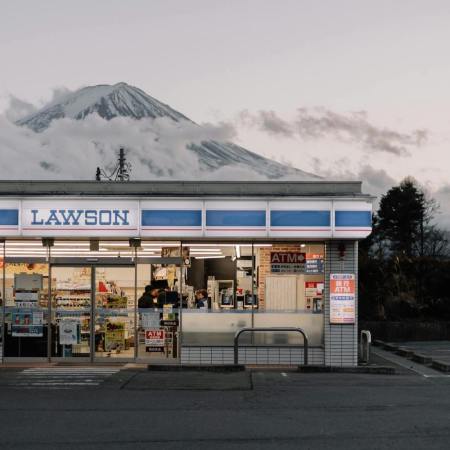 a japanese lawson konbini at dusk in front of a snow-covered mountain