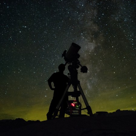 An astronomer using a telescope to look at the night sky