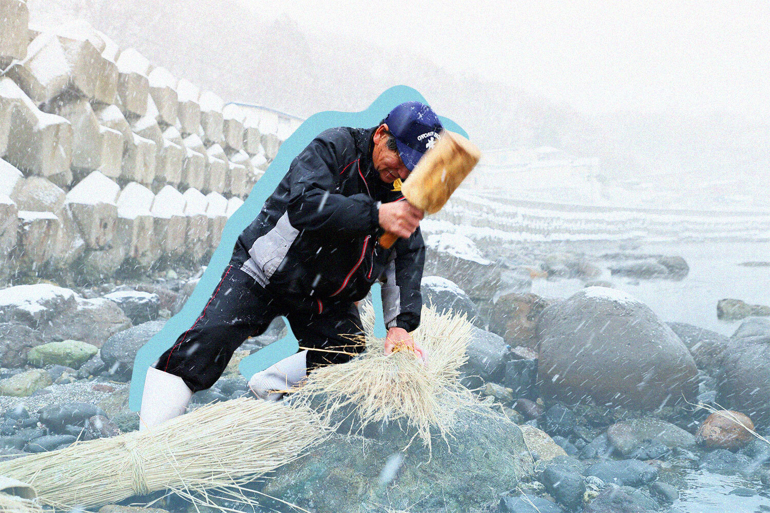 A Japanese man softens straw with a wooden hammer in heavy snow.