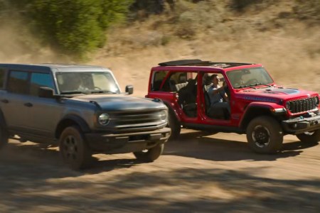A Jeep Wrangler Rubicon 4xe driving past a Ford Bronco in the Jeep Super Bowl 59 ad from 2025 called "Owner's Manual"