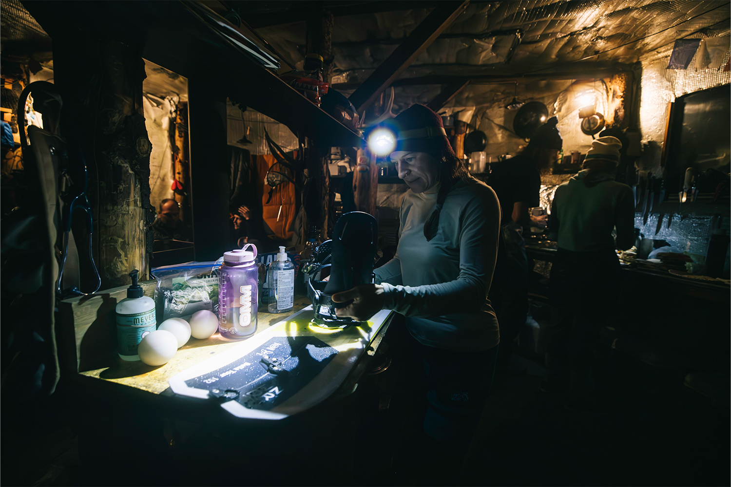 Another view from inside the yurt: a woman with a headlamp inspecting gear on a table.