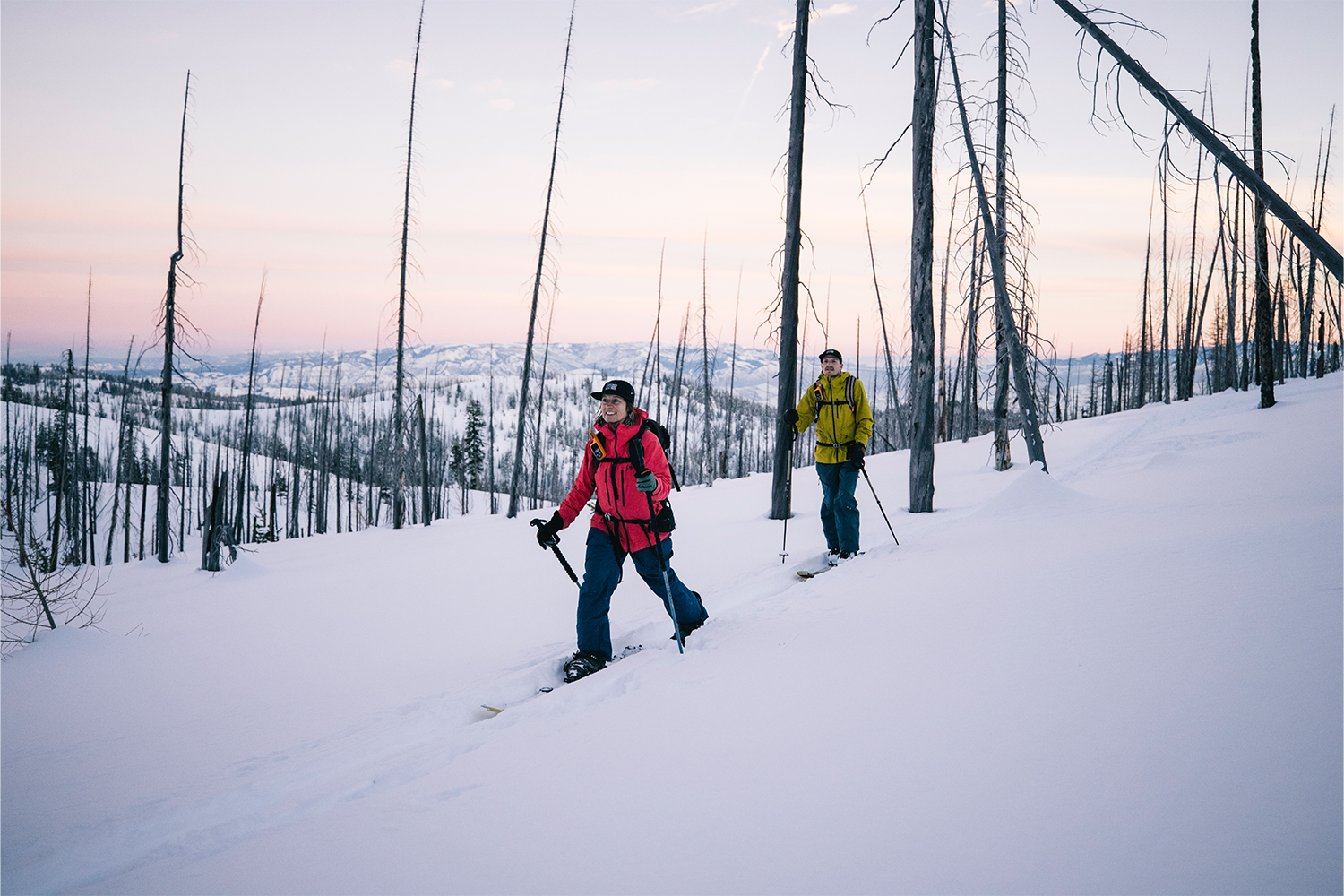 A pair of skiers smile while moving to their next run.
