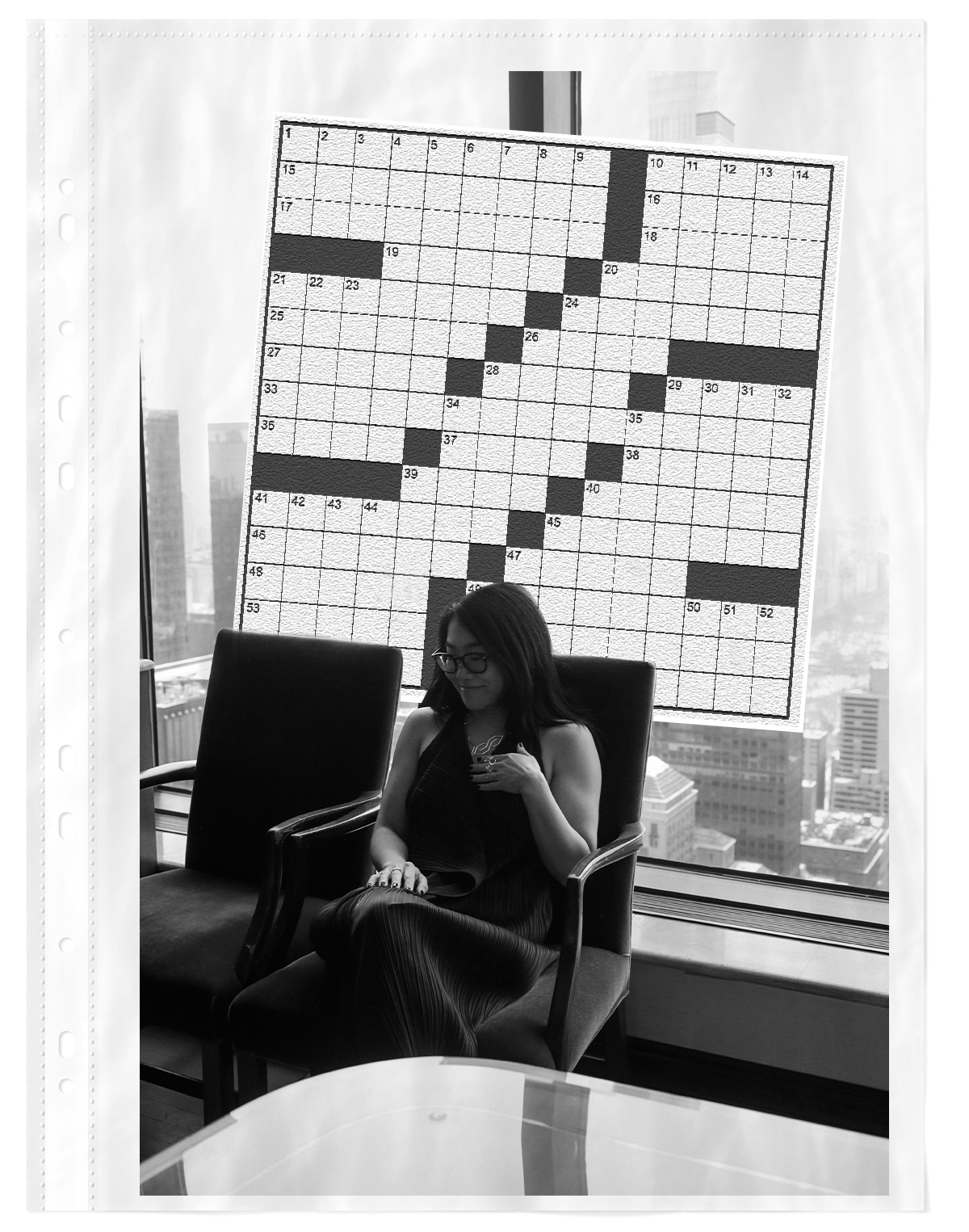 Wyna Liu sitting in a chair with a giant crossword behind her