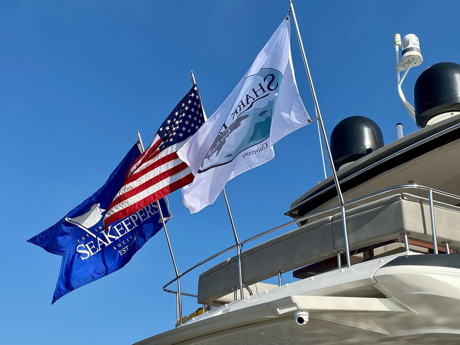 Three flags on the back of a yacht, including the American flag and one for the International SeaKeepers Society