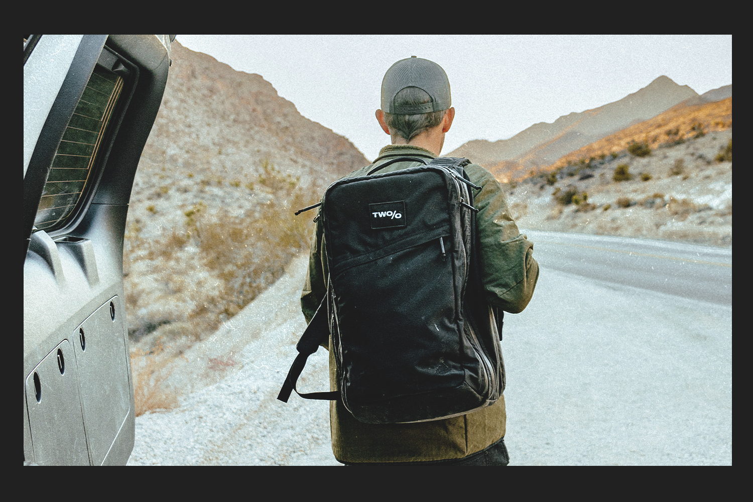 A shot of Michael Easter wearing his backpack and walking onto the street — captured from the trunk of a car.