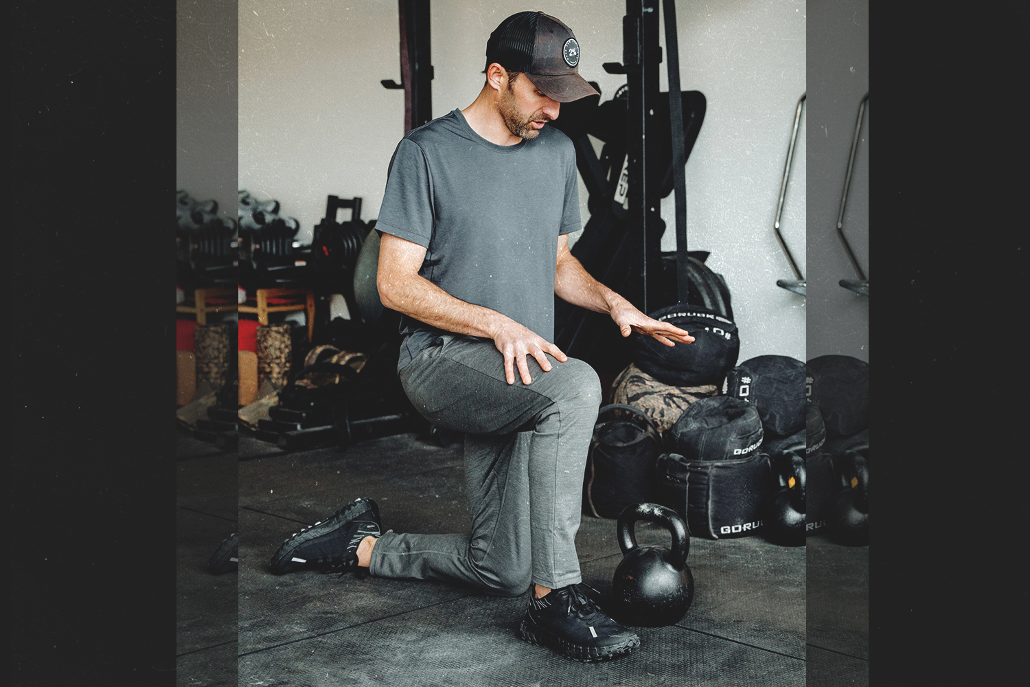 A photo of Michael Easter in a gym, kneeling next to a kettlebell.